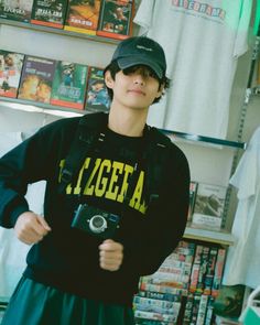 a young man holding a camera and wearing a hat