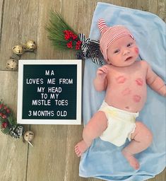 a baby laying on top of a blue blanket next to a sign that says love's me from my head to my mistle toes 3 months old