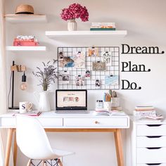 a white desk topped with a laptop computer next to a shelf filled with books and flowers