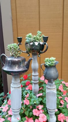 three metal vases with succulent plants in them sitting on top of flowers