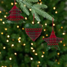 three ornaments hanging from a christmas tree with lights in the background