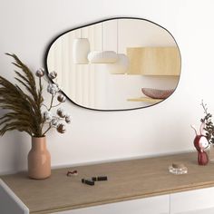 a mirror sitting on top of a dresser next to a vase with flowers in it