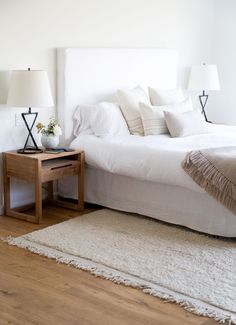 a bed with white sheets and pillows in a room