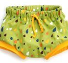 a pair of green shorts with yellow trims and colorful polka dots on the bottom