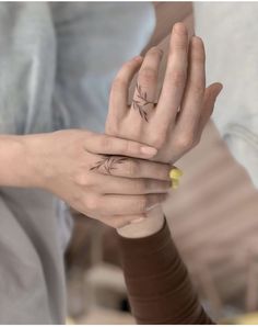 two people holding hands with tattoos on their fingers