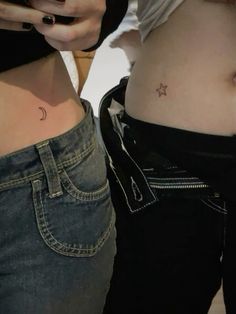 two women with small tattoos on their stomachs, one is holding a cell phone