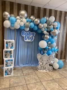 an elephant themed baby shower with blue and silver balloons on the wall, it's boy