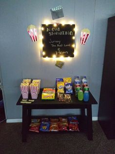 a table with popcorn, soda bottles and snacks on it in front of a sign that says an evening show