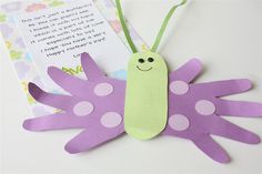 a purple and white paper butterfly sitting on top of a table next to a piece of paper