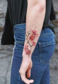 a woman's arm with flowers on it and her hand in the other direction