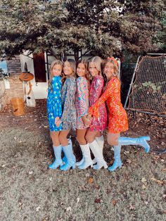 three girls in raincoats standing next to each other near a tree and fence