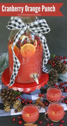 cranberry orange punch in a jar with two glasses and pine cones on the side