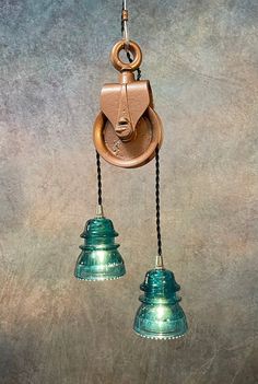 two hanging lights are attached to the wall with cords and hooks on them, one is green