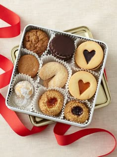 a box filled with assorted pastries next to a red ribbon on a table