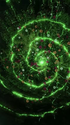 an aerial view of a green spiral in the middle of flowers and trees with lights