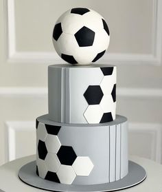 three tiered cake decorated with soccer balls on top of each other in black and white