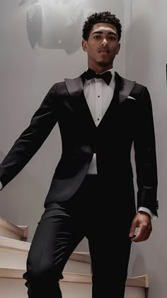 a young man in a tuxedo poses for the camera