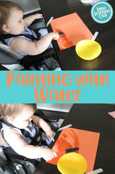 a baby sitting in a highchair playing with water and orange paper on the table