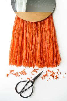 a pair of scissors sitting on top of a table next to an orange fringe and mirror