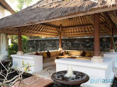 an outdoor seating area with a fountain in the center and thatched roof above it