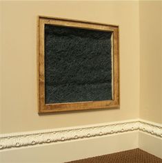 an empty room with a chalkboard hanging on the wall and carpeted flooring