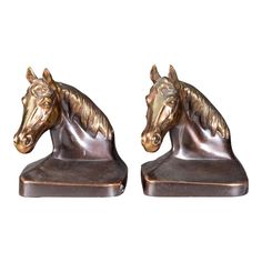 two bronze horse head bookends sitting on top of each other