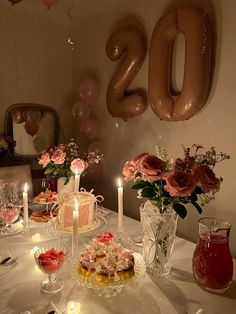 the table is set for a birthday party with candles and flowers in vases on it