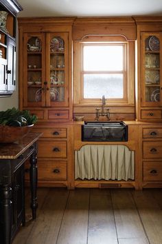 a kitchen with wooden cabinets and an old fashioned sink in the center, surrounded by wood flooring