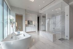 a large white bathroom with marble floors and walls, along with a walk in shower