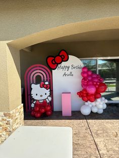 a hello kitty birthday party entrance with balloons and decorations on the front door to an apartment building