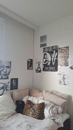 an unmade bed in a small room with posters on the wall and pictures above it