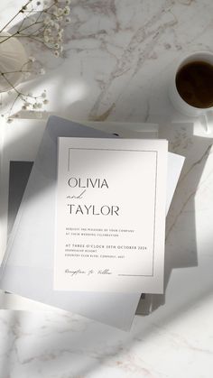 the wedding stationery is laid out next to a cup of coffee