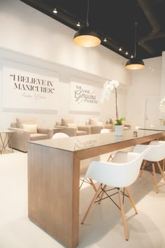 a table with white chairs in front of it and some pictures on the wall behind it