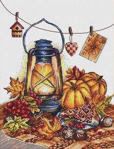 a cross stitch pattern with a lantern and autumn decorations