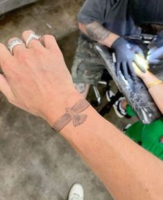 a person with a tattoo on their wrist holding something in one hand and an object in the other