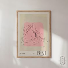 a drawing hangs on the wall in front of a white wall with a wooden frame