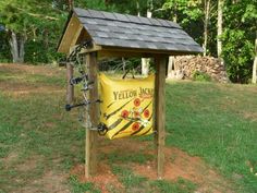 a yellow bag is attached to a wooden structure in the grass with trees behind it