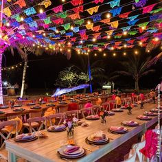 an outdoor dining area with tables and chairs covered in colorful paper garlands at night