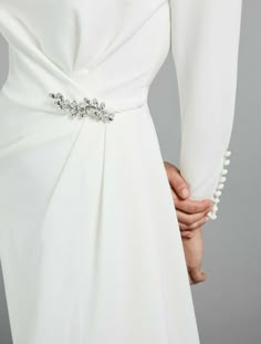 the back of a woman's white dress with beaded trims and long sleeves