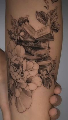 a woman's leg with flowers and books on it, in black and white