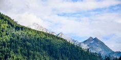 the mountains are covered with trees and clouds