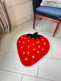 a large red strawberry rug on the floor next to a chair