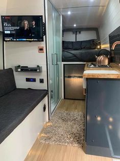 the interior of an rv with wood flooring and stainless steel appliances, including a television