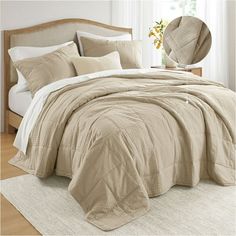 a bed with beige comforters and pillows in a bedroom