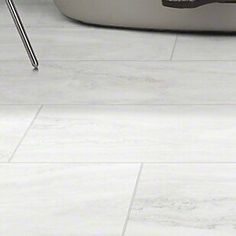 a bath tub sitting on top of a white tiled floor next to a toilet paper dispenser