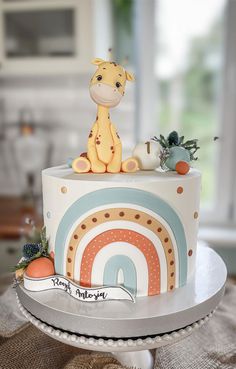 a giraffe sitting on top of a rainbow cake