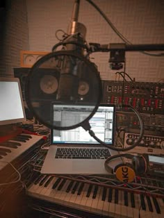 a laptop computer sitting on top of a keyboard next to a microphone and headphones