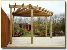 a wooden pergolan sitting on top of a wooden deck next to a building