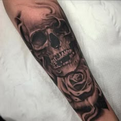 a man's arm with a skull and rose tattoo design on the left forearm