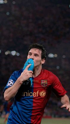 a man holding a blue object in his mouth while standing next to a soccer field